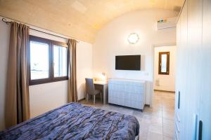 - une chambre avec un lit, un bureau et une télévision dans l'établissement Lamia del carrubo, à San Vito dei Normanni