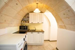 une cuisine avec un comptoir blanc et une arche dans l'établissement Lamia del carrubo, à San Vito dei Normanni