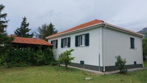a small white house with black windows and a yard at Sailing Forever Bungalow in Kaštela