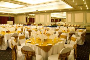 um grande salão de banquetes com mesas e cadeiras brancas em Regent Plaza Hotel & Convention Center em Carachi