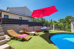 a red umbrella over a yard with chairs and a pool at Apartment City Peace in Rijeka