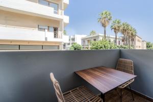 einen Holztisch und Stühle auf einem Balkon mit Palmen in der Unterkunft Island City Hotel in Rhodos (Stadt)