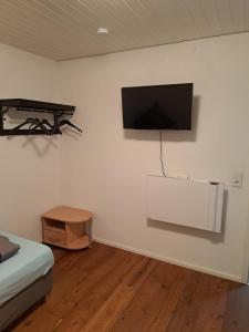 een kamer met een flatscreen-tv aan de muur bij Gästehaus Six Inn mit Gemeinschaftsküche bis 6 Personen in Uttenweiler