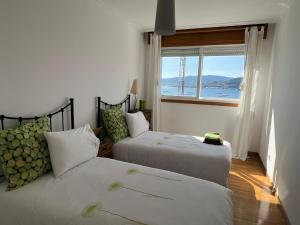 two beds in a room with a view of the ocean at VENTANAMAR CHAPELA in Redondela