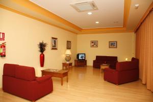 a living room with two red chairs and a tv at Hotel Mari Carmen in Guadix