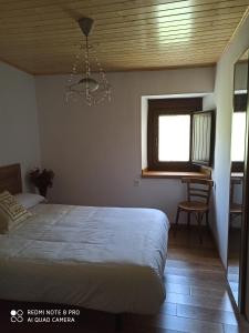 1 dormitorio con cama, ventana y lámpara de araña en CASA DA LOAIRA en Quiroga