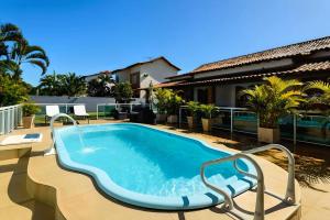 a swimming pool with a chair next to a house at Village Itaúna Inn in Saquarema