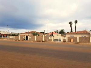una calle vacía con una valla y palmeras en Bushbabies-Inn Self-Catering Accommodation en Swakopmund