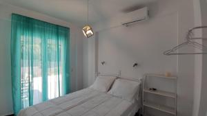 a bedroom with a bed with a green curtain and a window at SUN KISS HOUSES Sun Kiss Houses B in Áyios Spirídhon