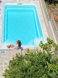 une femme assise sur une chaise à côté d'une piscine dans l'établissement Oniropetra Luxury Suites, à Kastéllion