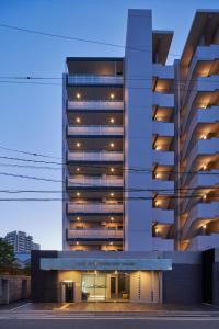 un edificio alto con luces en el costado. en ALFACIO RIVERSIDE STAY HAKATA, en Fukuoka