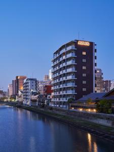 un edificio alto con un cartello sul lato di un fiume di ALFACIO RIVERSIDE STAY HAKATA a Fukuoka