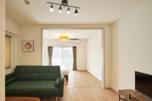 sala de estar con sofá verde y cama en ALFACIO RIVERSIDE STAY HAKATA, en Fukuoka