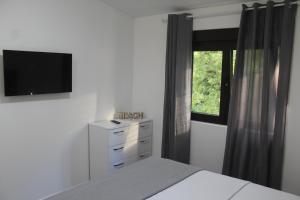 una camera da letto con un letto e una televisione a parete di MIA CASA Apartmens a Budua