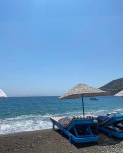 two lounge chairs and an umbrella on the beach at Yildiz Ahşap Evleri in Datca