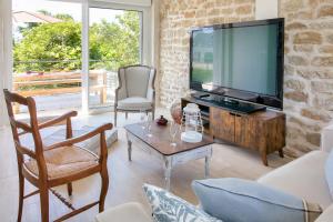 een woonkamer met een televisie en een tafel en stoelen bij Paisible escale pres de la plage in Plobannalec-Lesconil