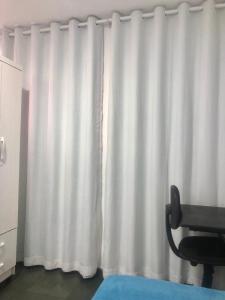 a white curtain in a room with a chair at Pousada 714 in Brasilia