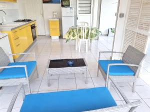a patio with three chairs and a table and a kitchen at Appartement cosy avec piscine privée, Le François, 40 m² in Le François