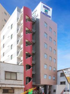 a tall red building with a sign on it at HOTEL LiVEMAX BUDGET Fuchu Annex in Fuchu