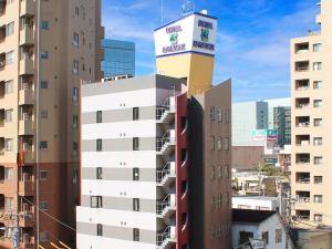 ein hohes Gebäude mit einem Turm darüber in der Unterkunft HOTEL LiVEMAX BUDGET Fuchu Annex in Fuchu