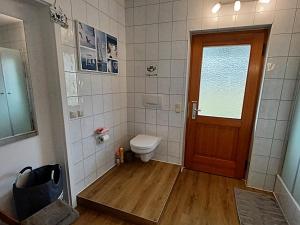 a bathroom with a toilet and a wooden door at Rottaler Ferienhaus - Rottaler Oachkatzl in Roßbach