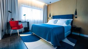 sypialnia z niebieskim łóżkiem i czerwonym krzesłem w obiekcie Hills Hotel Lisboa w Lizbonie