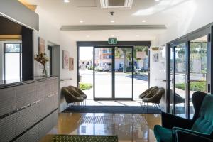 a lobby with two chairs and an open door at Joondalup City Hotel in Perth