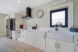 una cocina con armarios blancos y un reloj en la pared en Seaview Lodge Apartment 'Sleeping 4 Guests', en Tieveborne