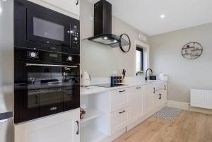 a kitchen with white cabinets and a black oven at Seaview Lodge Apartment 'Sleeping 4 Guests' in Tieveborne
