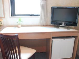 a computer desk with a television on top of it at HOTEL LiVEMAX BUDGET Fuchu Annex in Fuchu