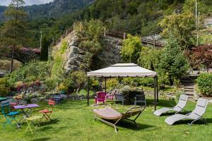 a group of chairs and an umbrella in the grass at Le Moulin Des Aravis in Pontboset