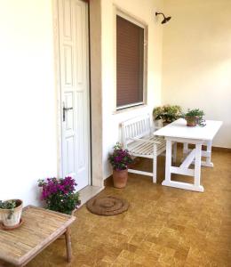 un porche con un banco, una mesa y flores en CASE VACANZE 'RICCIO E SALVIA' A S. M. DI LEUCA, en Marina di Leuca