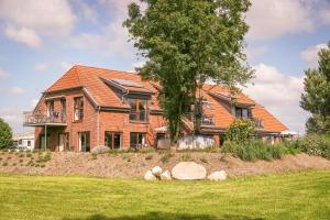een stenen huis met een oranje dak bij FEWO Morgenröte - Weserblick -Harriersand in Schwanewede