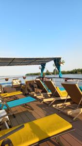 a group of lounge chairs and tables on a boat at Hotel Plutitor Egreta1 in Sfântu Gheorghe