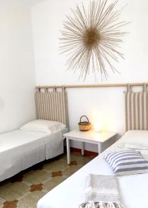 Habitación con 2 camas, mesa y reloj en CASE VACANZE 'RICCIO E SALVIA' A S. M. DI LEUCA, en Marina di Leuca