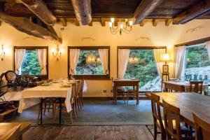 uma sala de jantar com mesas, cadeiras e janelas em Le Moulin Des Aravis em Pontboset