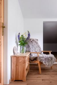 a living room with a chair with a vase of flowers at Lysečinská bouda in Horní Maršov