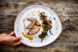 a person holding a plate of food on a table at Trasti & Trine Boutique Hotel in Alta