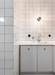 a white bathroom with a sink and white tiles at Trilogy Experimental in Thessaloniki