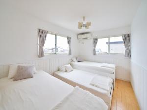 2 Betten in einem Zimmer mit 2 Fenstern in der Unterkunft Villa OLIVE Sajima -佐島の丘- ペット可 in Yokosuka