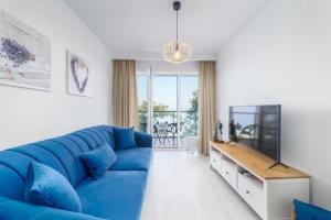 sala de estar con sofá azul y TV en Apartment next to the beach with sea view Ustronie Morskie, en Ustronie Morskie