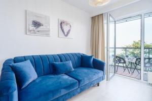 ein blaues Sofa im Wohnzimmer mit Fenster in der Unterkunft Apartment next to the beach with sea view Ustronie Morskie in Ustronie Morskie