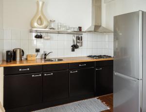 een keuken met zwarte kasten en een roestvrijstalen koelkast bij Center Appartement Apeldoorn in Apeldoorn