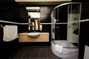 a bathroom with a sink and a tub and a mirror at Apart Hotel Bonjour Cluj in Cluj-Napoca