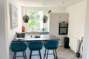 a kitchen with a counter and two blue bar stools at Standout 2BD Coastal Cottages in South Devon in Shaldon