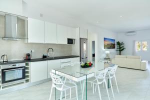uma cozinha com armários brancos e uma mesa e cadeiras em Villa Boutique Can Bellotera em Sant Jordi