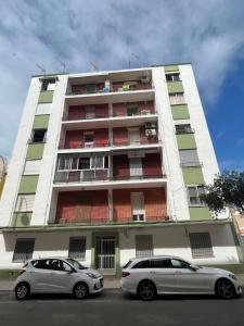 twee auto's geparkeerd voor een hoog gebouw bij Apartamento No5 in Gandía