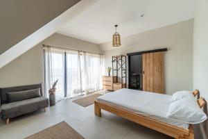 a bedroom with a bed and a chair in it at Viešbutis SAKAI sodyboje Gribžė in Gribžiniai