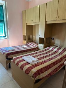 two beds in a room with wooden cabinets at Hotel Aurora in La Spezia