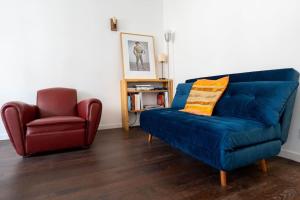 - un salon avec un canapé bleu et un fauteuil rouge dans l'établissement T2 Tout Confort avec terrasse- Métro Saint Cyprien, à Toulouse
